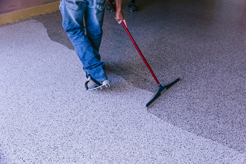 Horsley Employee spreading clear coat over a flake garage floor
