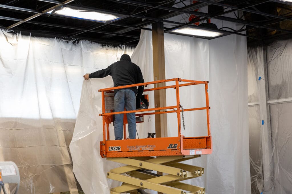 Dust Containment Professional uses a scissor lift to install dust curtains
